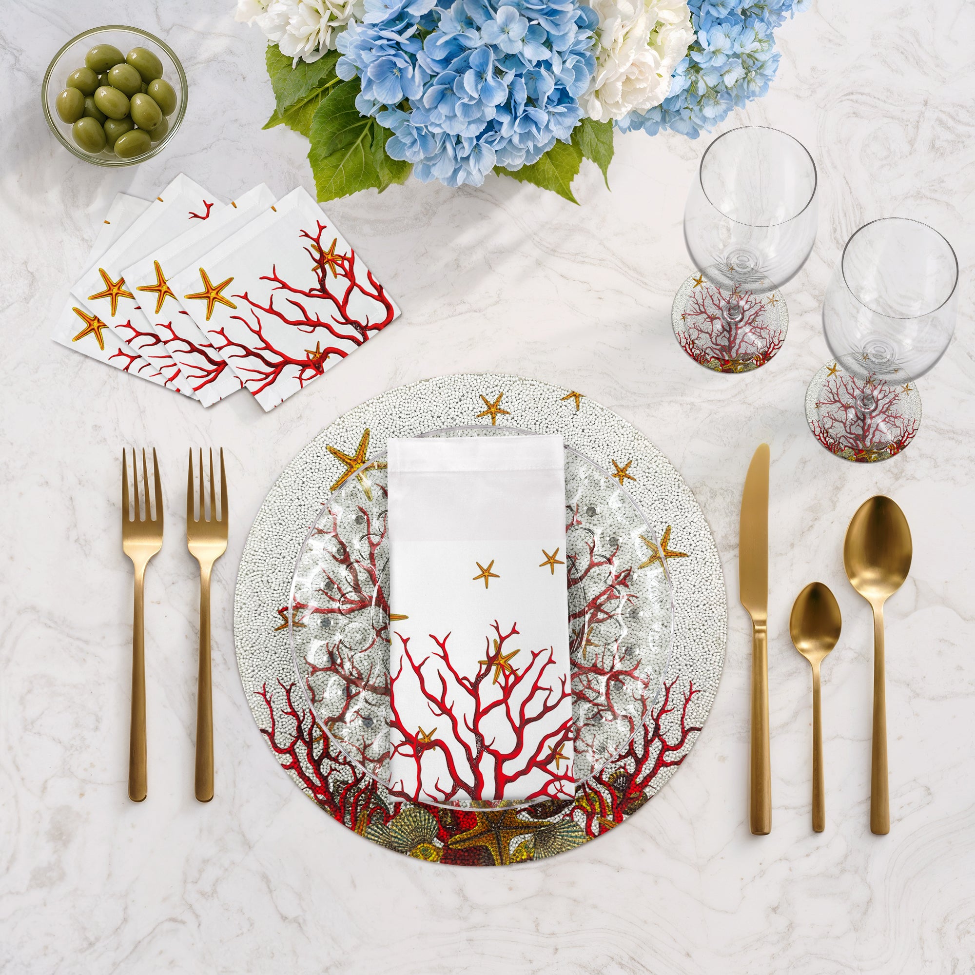 Table setting with coral-themed plates, napkins, and cutlery on a marble surface.