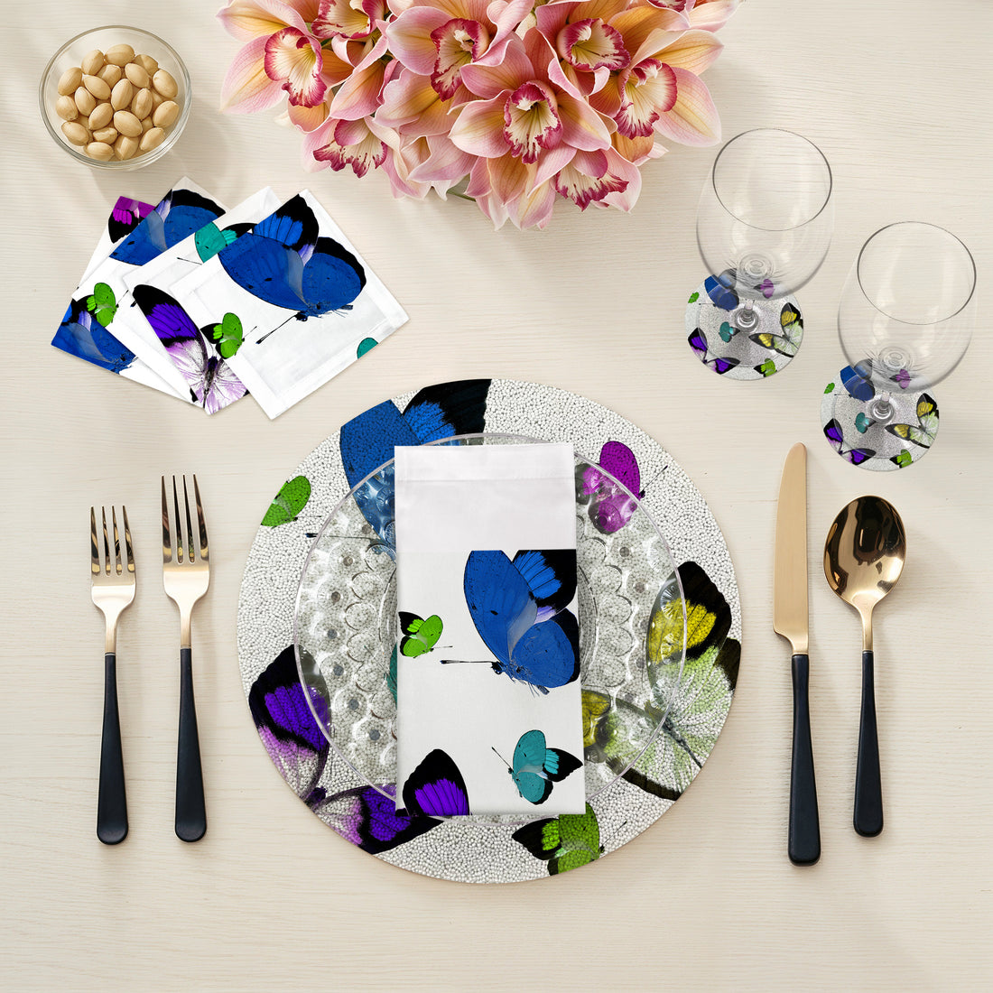 Dinner table setting with butterfly-themed plates, napkins, and cutlery on a light background.