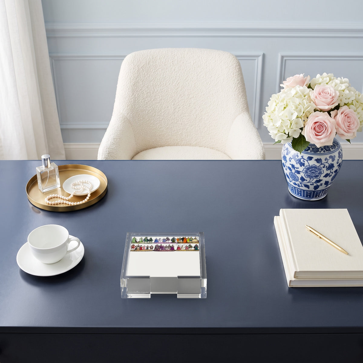 Costumes 1830 notepad in a clear acrylic holder on a navy desk by Nicolette Mayer